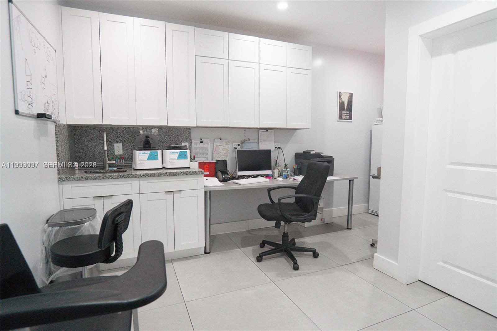 A medical office features white cabinetry, a granite countertop, a computer desk, and tile flooring — 2268 SW 8th St, Miami FL 33135, MIAMI, FL