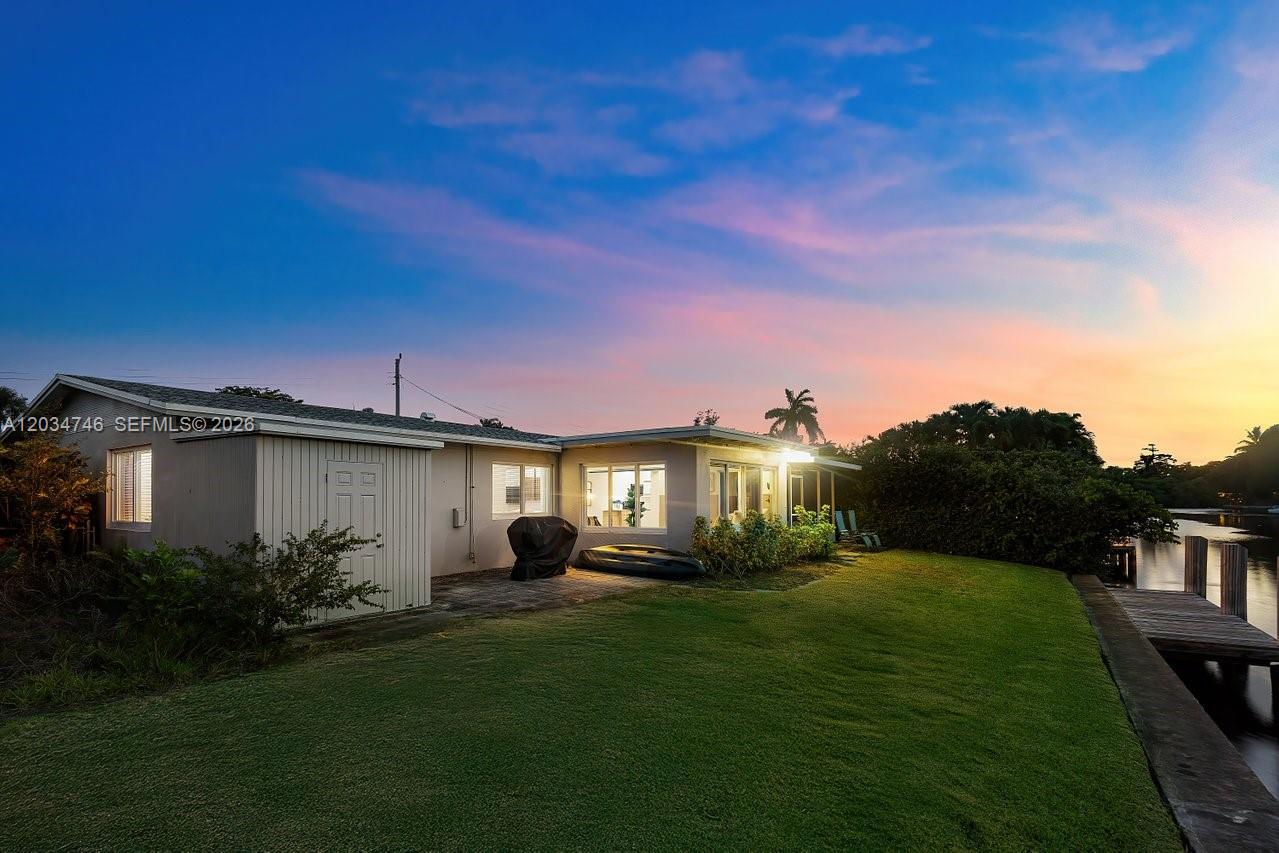 The exterior of a single-story house features a grassy lawn, a patio, and a dock — 509 NE 29th St, Wilton Manors FL 33334, WILTON MANORS, FL
