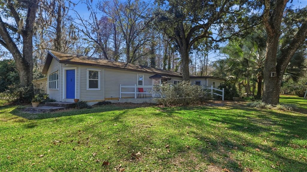 A single-story house with light siding, a blue front door, and a wooden deck — 10565 BESSEMER STREET, NEW PORT RICHEY, FL