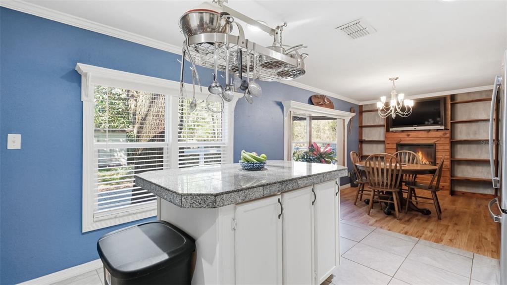 A kitchen with a granite-topped island, hanging pot rack, and an adjacent dining area — 10565 BESSEMER STREET, NEW PORT RICHEY, FL
