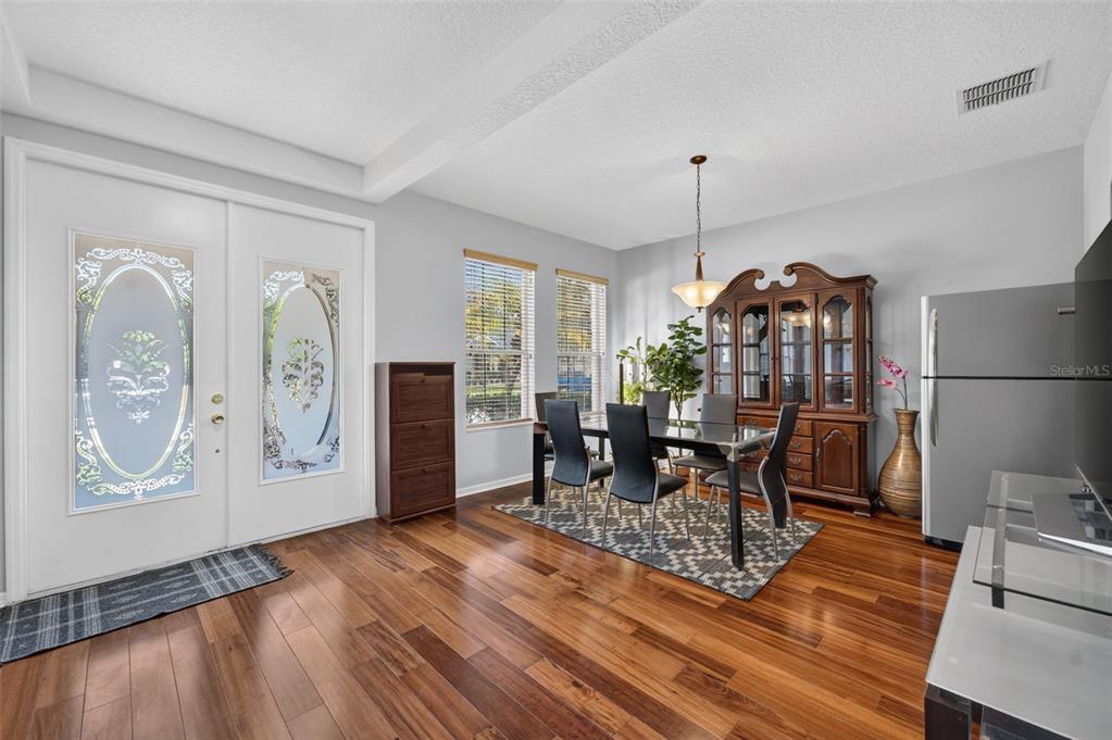 A dining area features a glass-top table, black chairs, a wooden hutch, and hardwood floors — 7438 CHELSEA HARBOUR DRIVE, ORLANDO, FL