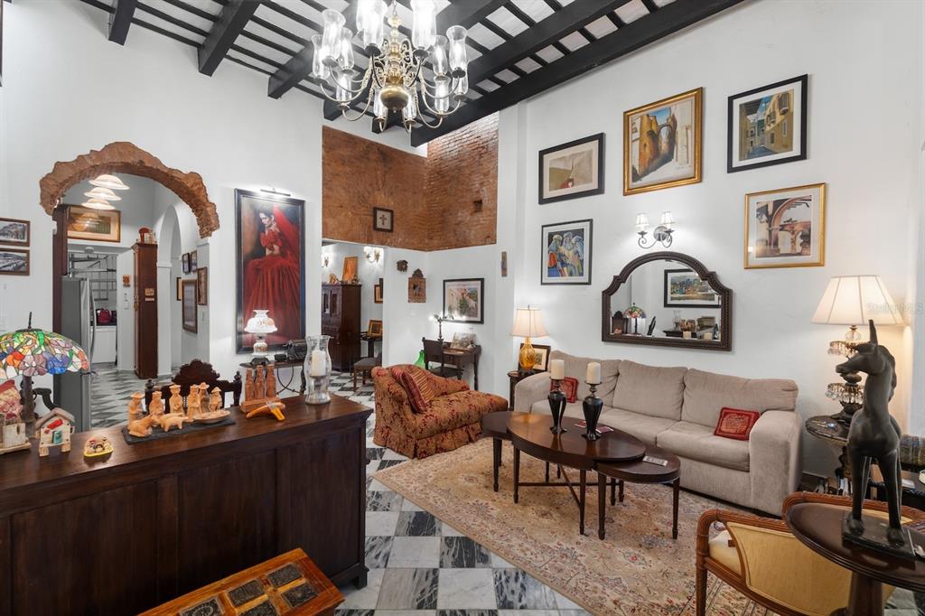A living room features high ceilings with exposed beams, marble floors, and a brick wall — 422 NORZAGARAY, SAN JUAN, PR
