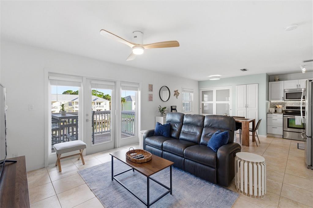 A living room with a dark leather sofa, coffee table, and sliding glass doors to a balcony — 5174 BEACH DRIVE SE UNIT D, ST PETERSBURG, FL