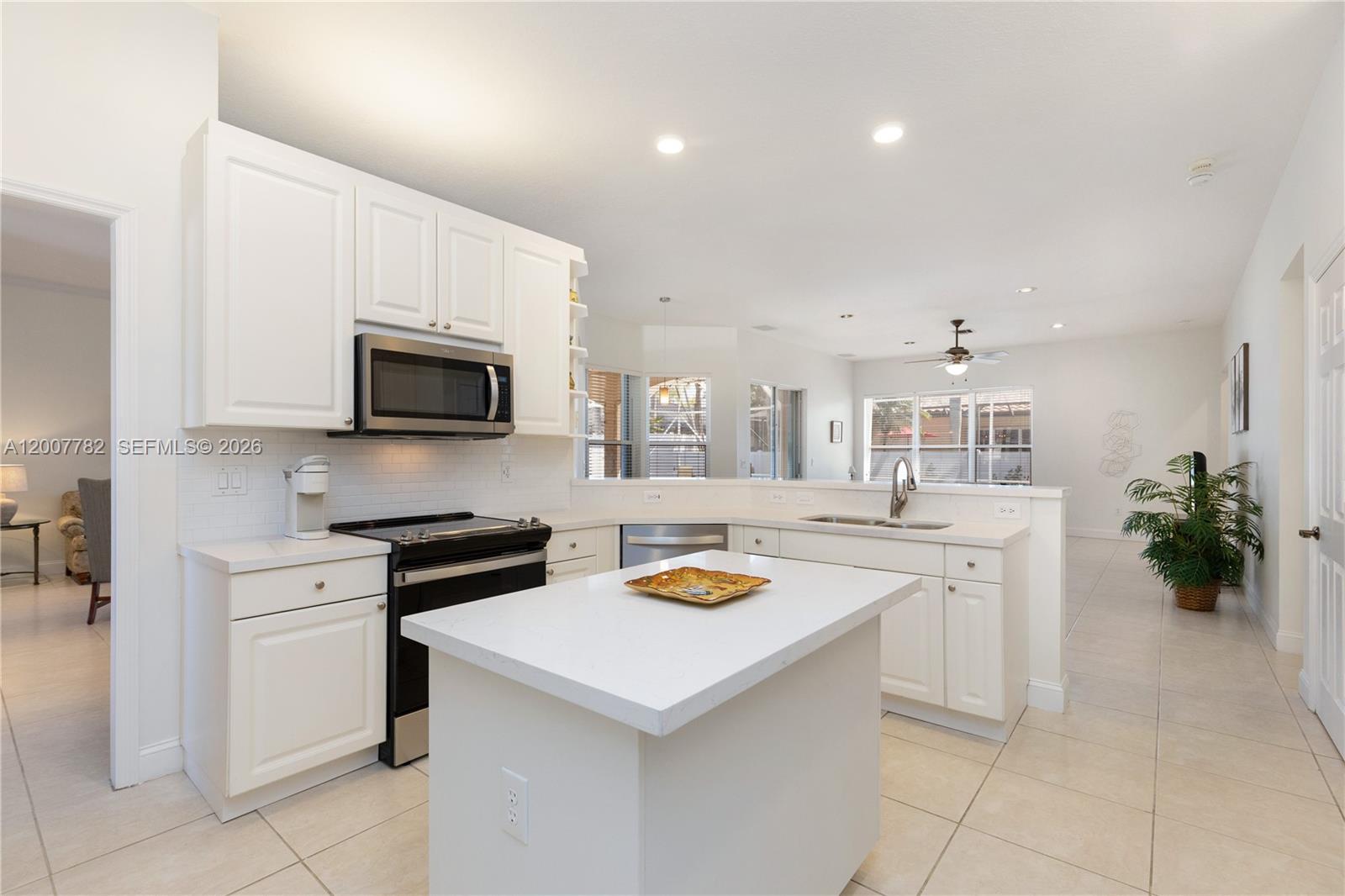 A bright kitchen features white cabinets, a central island, and stainless steel appliances — 15966 SW 3rd St, Pembroke Pines FL 33027, PEMBROKE PINES, FL