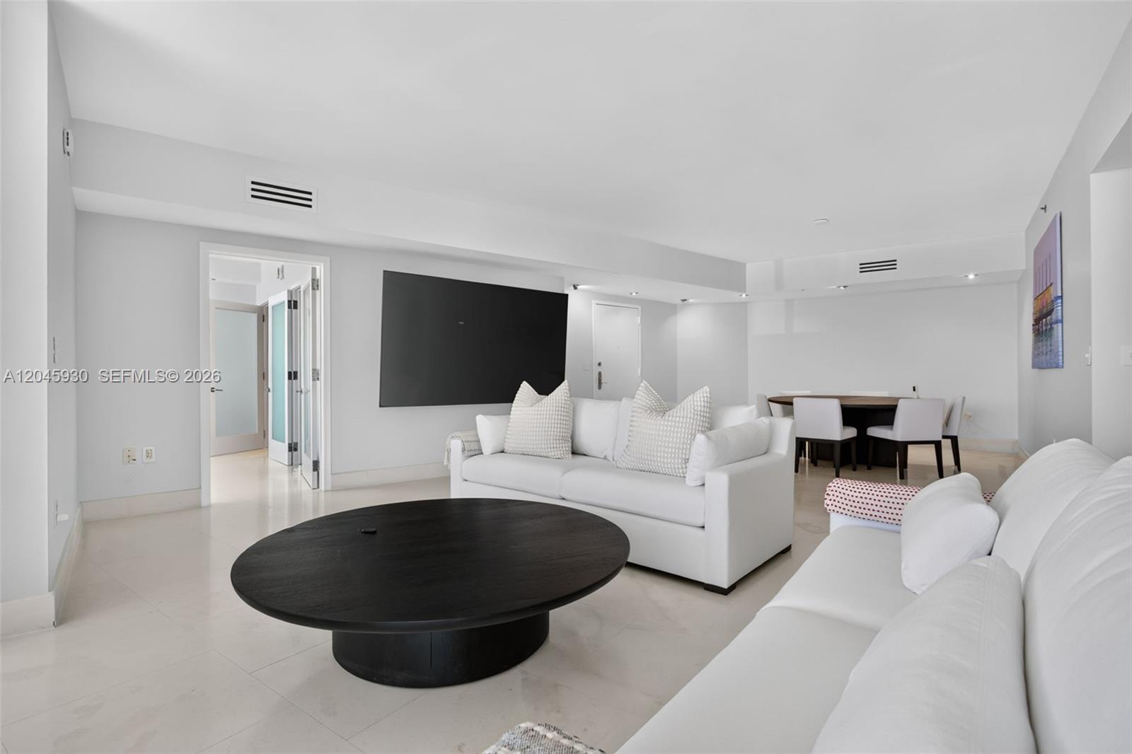 A living room features white sofas, a round black coffee table, and floor-to-ceiling balcony windows — 400 Alton Rd # 706, Miami Beach FL 33139, MIAMI BEACH, FL
