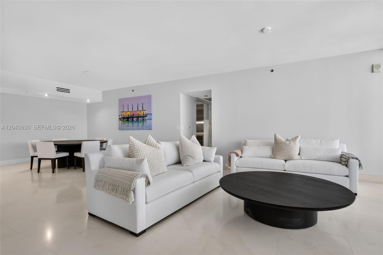 A living room features white sofas, a large round black coffee table, and a dining area — 400 Alton Rd # 706, Miami Beach FL 33139, MIAMI BEACH, FL