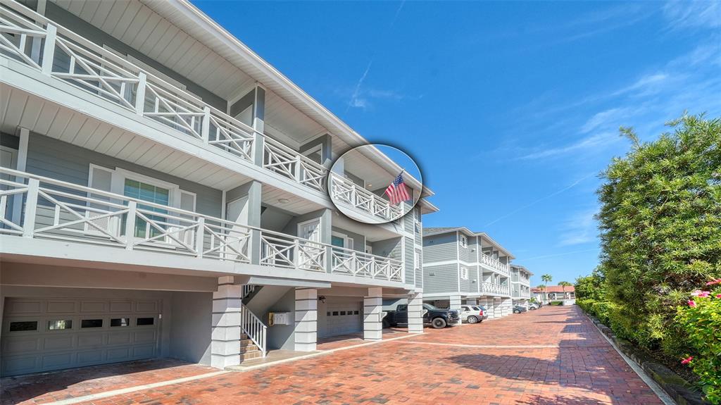An exterior view of a multi-story apartment building with a brick driveway and American flag — 1564 STICKNEY POINT ROAD UNIT 303, SARASOTA, FL