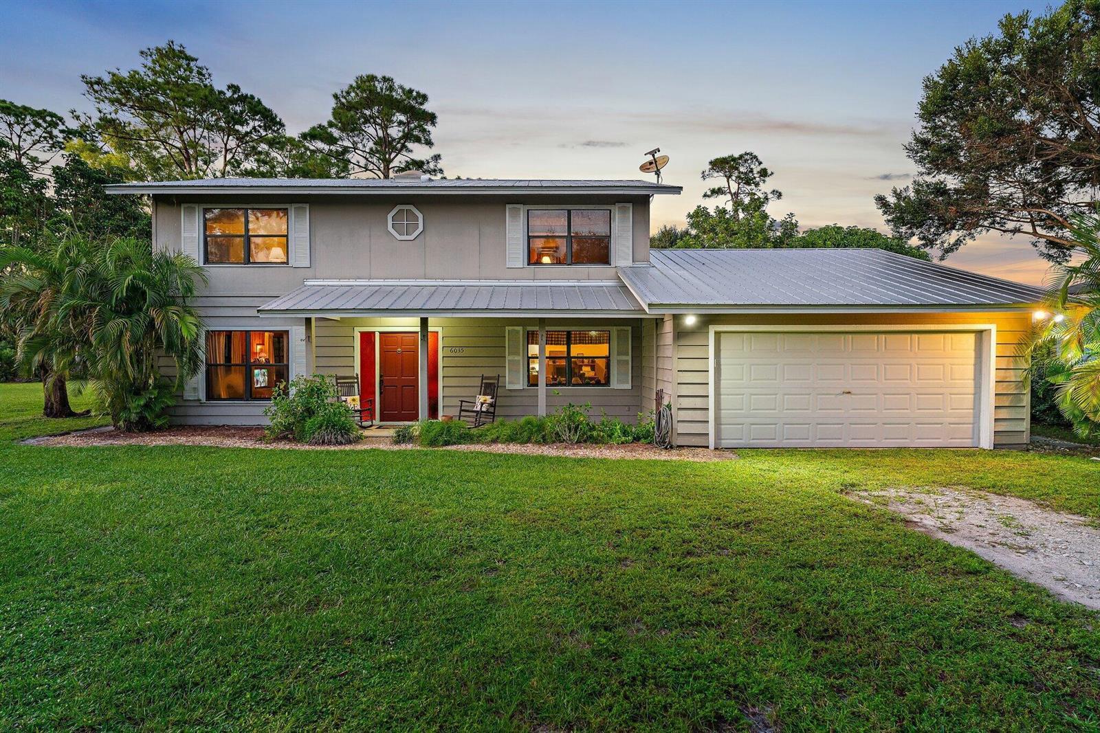 A two-story house with a metal roof, gray siding, and an attached garage — 6035 N 180th St Street N, Jupiter FL 33458, JUPITER, FL
