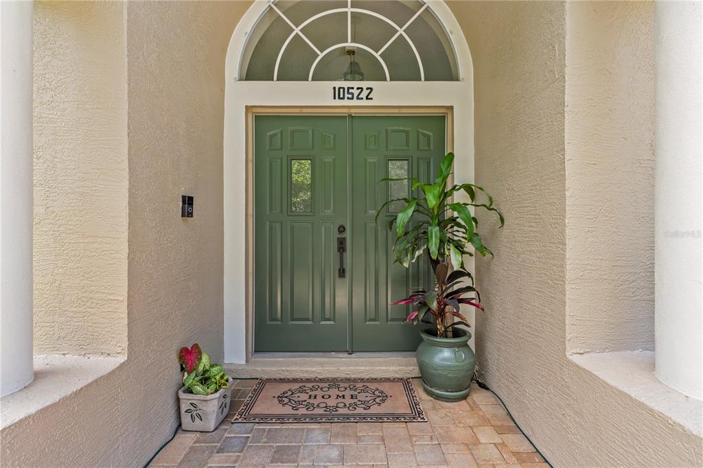 A single-story house with a beige exterior, arched windows, and a landscaped front yard — 10522 CHAMBERS DRIVE, TAMPA, FL
