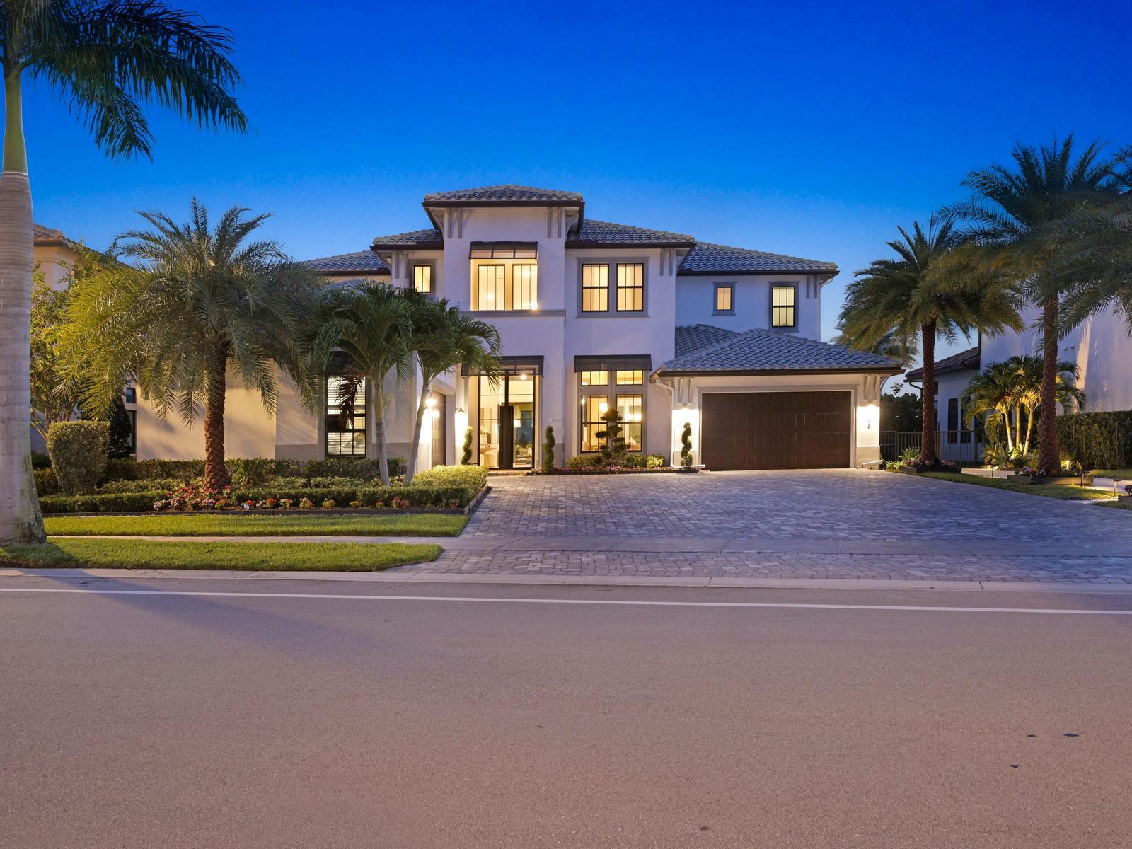 A two-story house with a paved driveway, palm trees, and a dark garage at dusk — 8785 Parkland Bay Drive, Parkland FL 33076, PARKLAND, FL