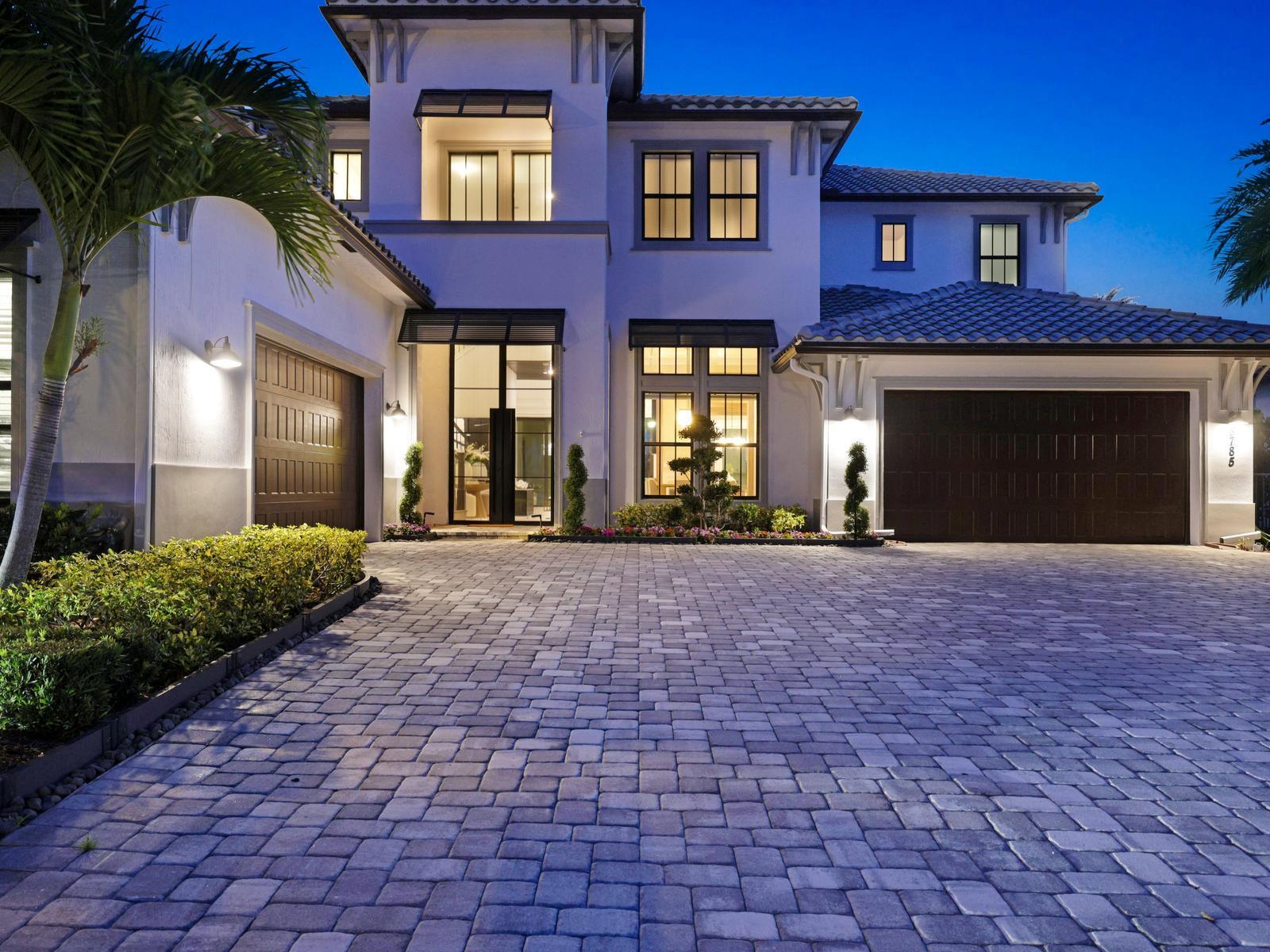 A two-story house exterior features a paved driveway, two garage doors, and a glass entryway — 8785 Parkland Bay Drive, Parkland FL 33076, PARKLAND, FL