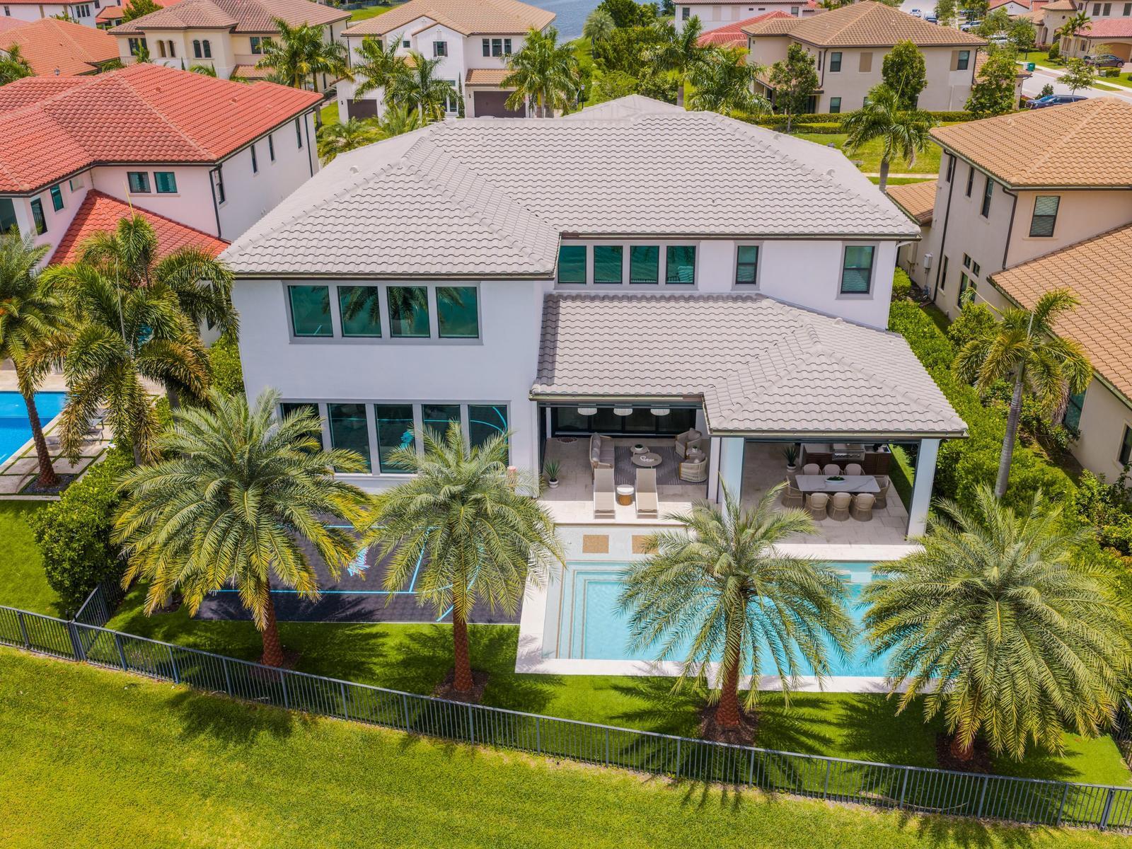 An aerial view of a two-story house with a pool, patio, and palm trees — 8785 Parkland Bay Drive, Parkland FL 33076, PARKLAND, FL