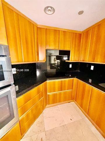 A kitchen features light wood cabinets, black countertops, and a built-in double oven — 9595 Collins Ave # I, Surfside FL 33154, SURFSIDE, FL
