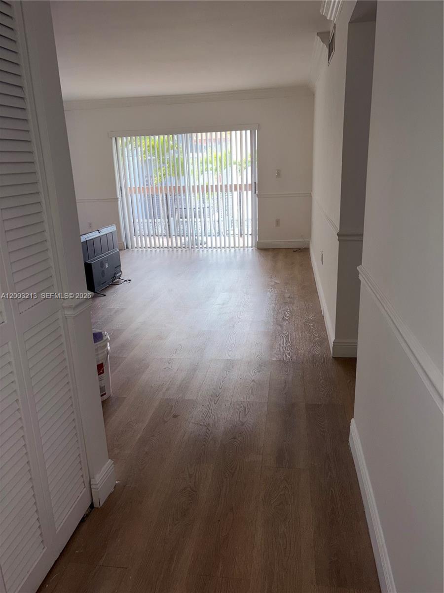 An empty living room features wood-look flooring, white walls, and vertical blinds over a door — 401 NW 72nd Ave # D, Miami FL 33126, MIAMI, FL