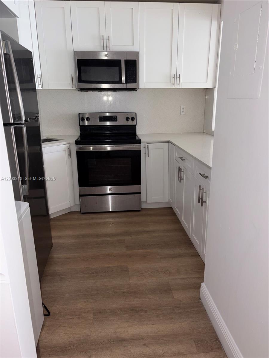 This kitchen features white cabinets, stainless steel appliances, and light-colored countertops — 401 NW 72nd Ave # D, Miami FL 33126, MIAMI, FL