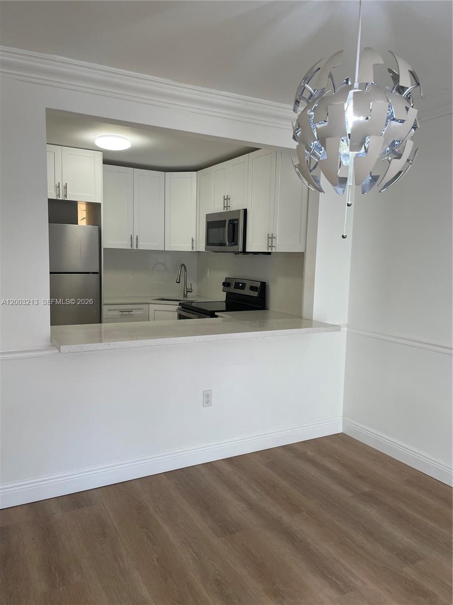A kitchen with white cabinets and stainless steel appliances opens to a dining area — 401 NW 72nd Ave # D, Miami FL 33126, MIAMI, FL