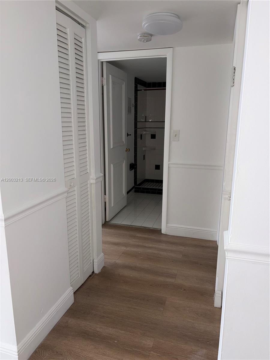 A hallway with wood-look flooring leads to a bathroom with a tiled shower — 401 NW 72nd Ave # D, Miami FL 33126, MIAMI, FL