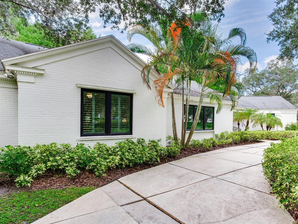 A white brick house with black-framed windows and a palm tree sits beside a driveway — 3401 S ALMERIA AVENUE, TAMPA, FL