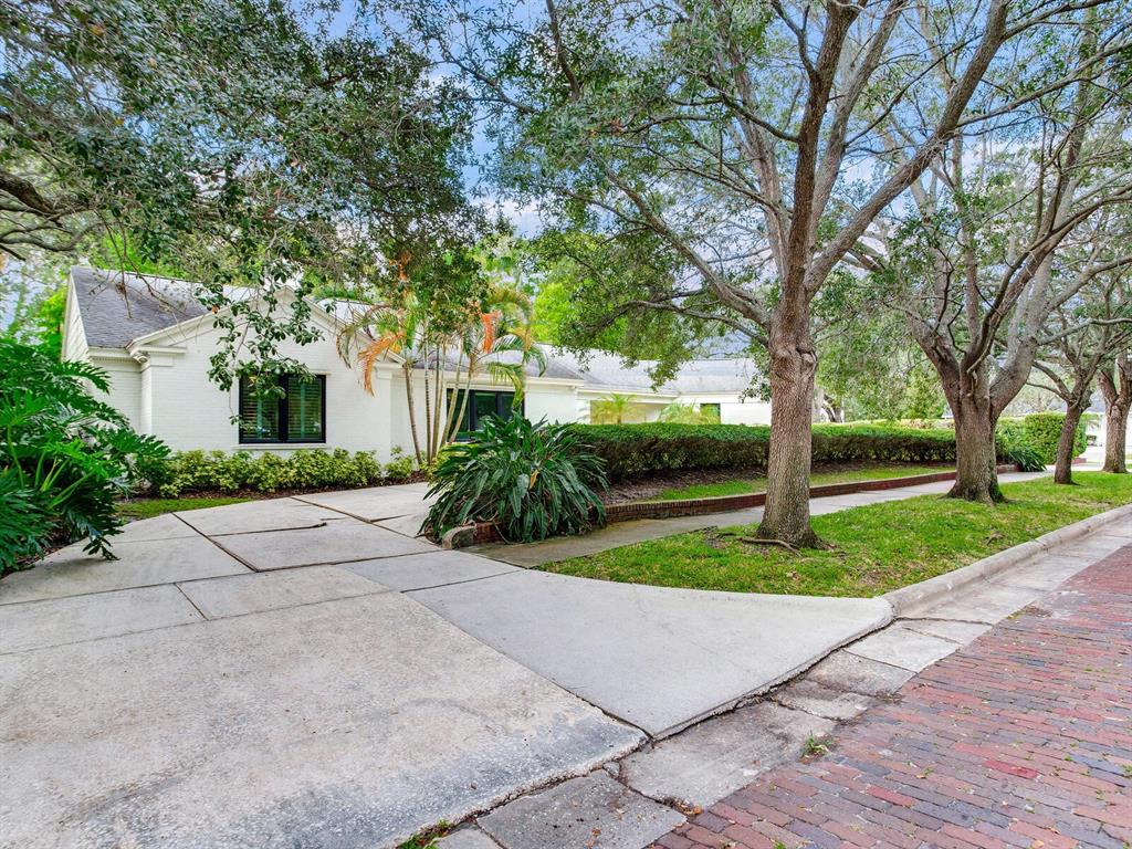 A white brick house with a concrete driveway sits behind a brick street and trees — 3401 S ALMERIA AVENUE, TAMPA, FL