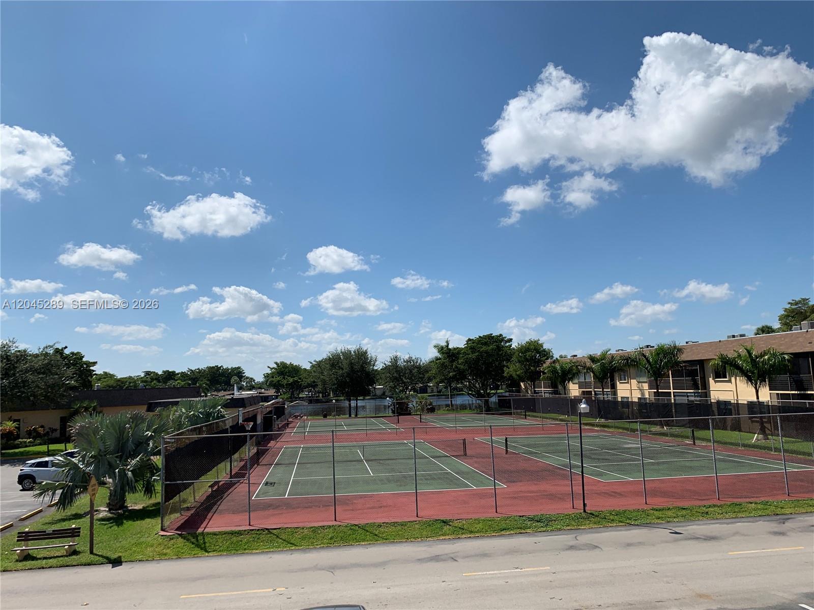 An outdoor view shows two tennis courts enclosed by chain-link fencing near residential buildings — 201 Berkley Rd # 204, Hollywood FL 33024, HOLLYWOOD, FL