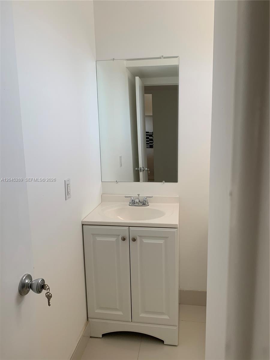 A small bathroom features a white vanity cabinet, a sink, and a wall-mounted mirror — 201 Berkley Rd # 204, Hollywood FL 33024, HOLLYWOOD, FL