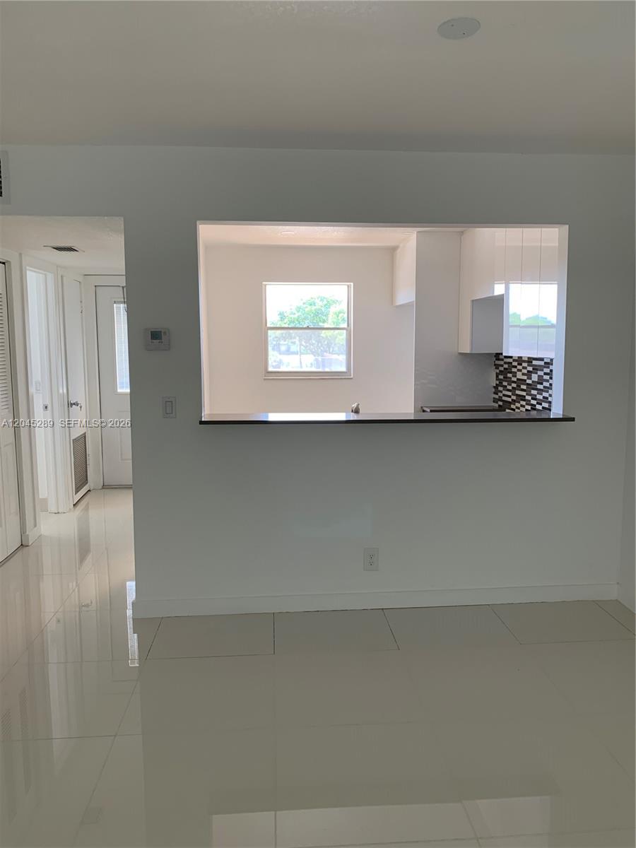 A view of a kitchen pass-through window with a breakfast bar and tiled flooring — 201 Berkley Rd # 204, Hollywood FL 33024, HOLLYWOOD, FL