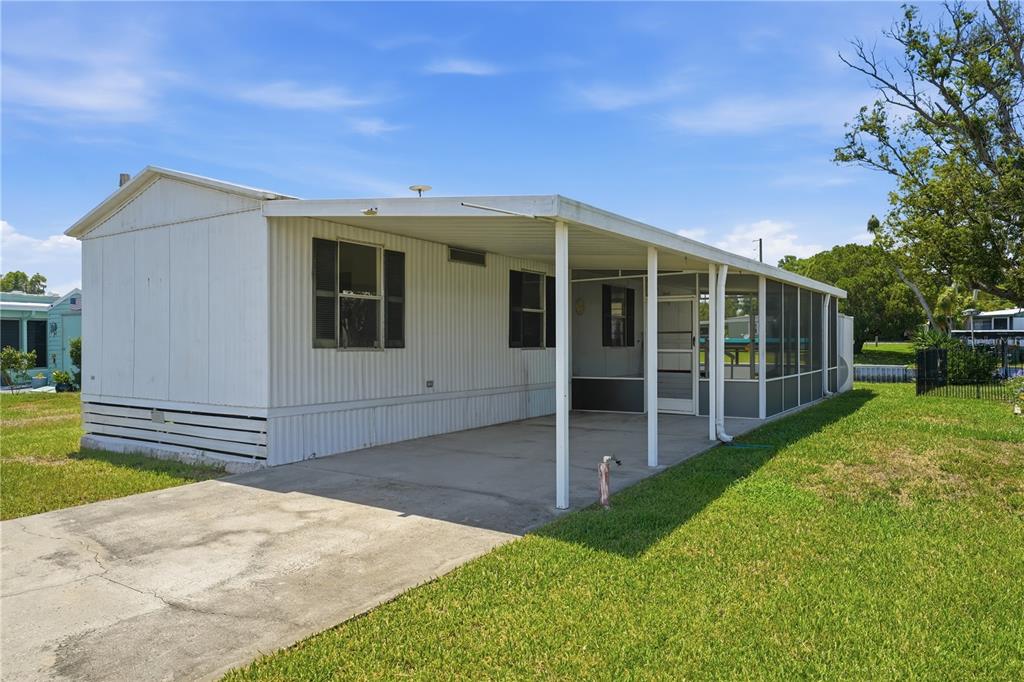 A white mobile home features a concrete driveway, a covered carport, and a screened-in porch — 30107 GREEN BAY DRIVE, TAVARES, FL
