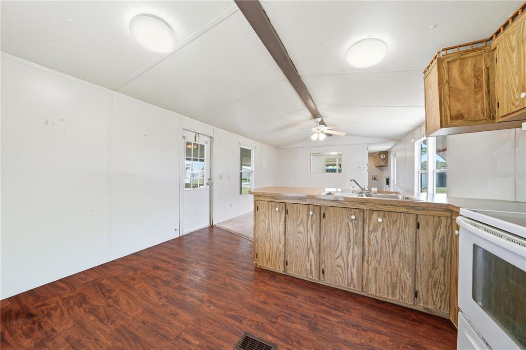 A kitchen with wood cabinets, a laminate countertop, and dark wood-look flooring — 30107 GREEN BAY DRIVE, TAVARES, FL