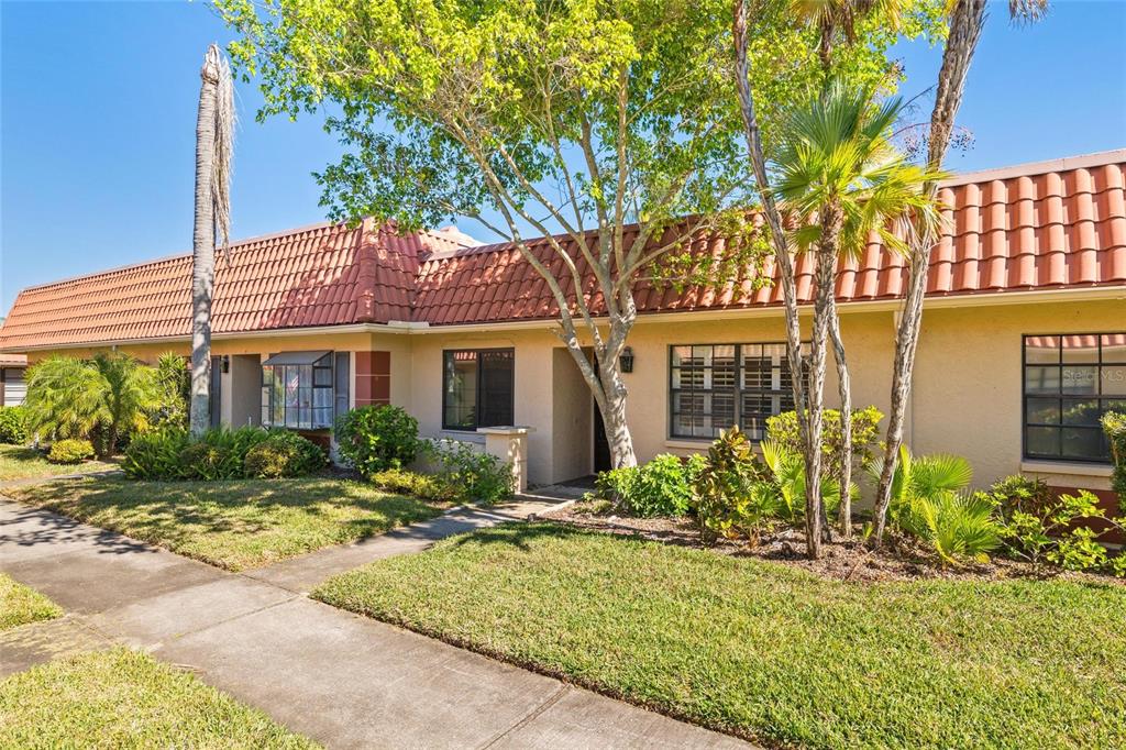 A single-story house with a red tile roof, beige stucco walls, and a front walkway — 19029 US HIGHWAY 19 HIGHWAY N UNIT 24C, CLEARWATER, FL