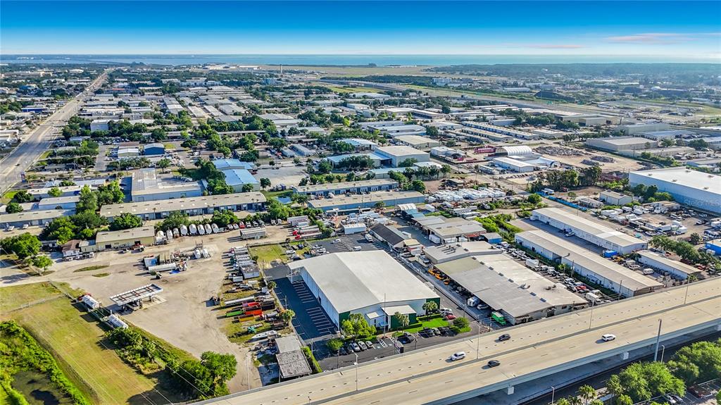 An aerial view shows industrial warehouses and commercial buildings situated next to a highway — 4677 118TH AVENUE N, CLEARWATER, FL