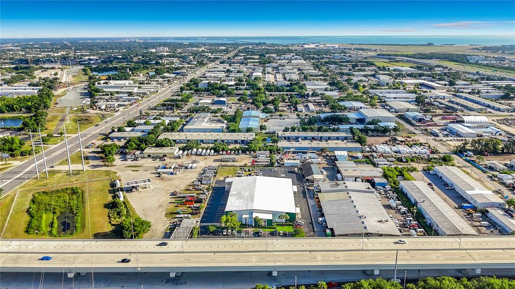 An aerial view shows a highway overpass in the foreground and industrial buildings beyond — 4677 118TH AVENUE N, CLEARWATER, FL