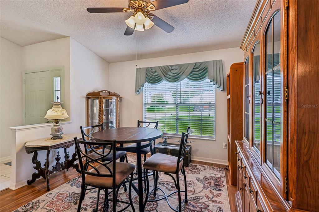 A dining room features a round wooden table, four chairs, a hutch, and a ceiling fan — 25111 BONNIE BLUE COURT, LEESBURG, FL