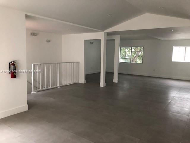 An open, unfurnished room features gray tile flooring, white walls, and a white stair railing — 929 Collins Ave # 2A, Miami Beach FL 33139, MIAMI BEACH, FL