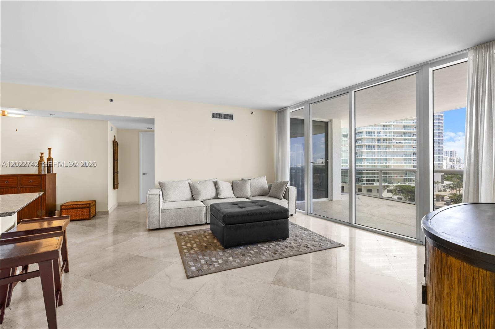 A living room features light tile floors, a grey sectional sofa, and floor-to-ceiling glass doors — 400 Alton Rd # 907, Miami Beach FL 33139, MIAMI BEACH, FL