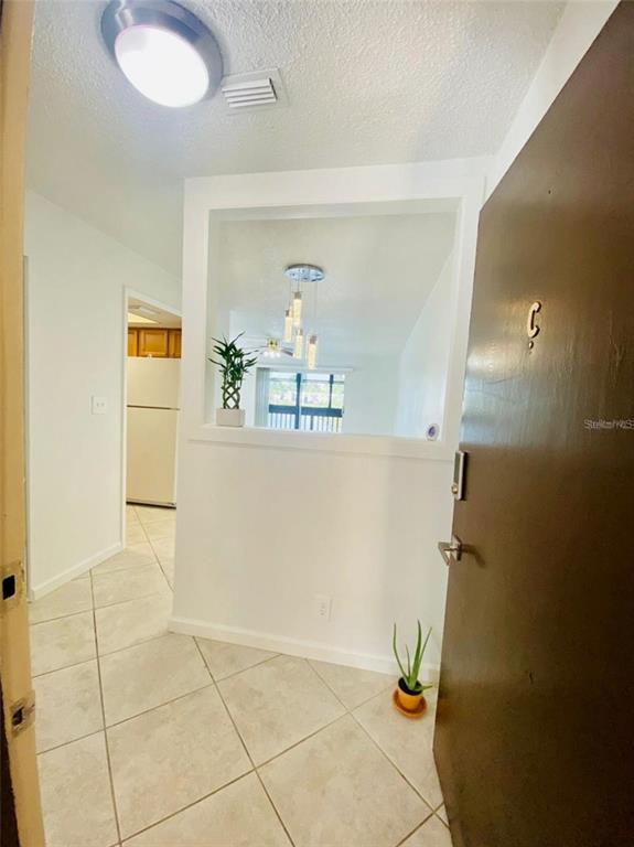 An entryway with tile flooring leads to a kitchen and a living area with pendant lighting — 633 N KEENE ROAD APT C, CLEARWATER, FL