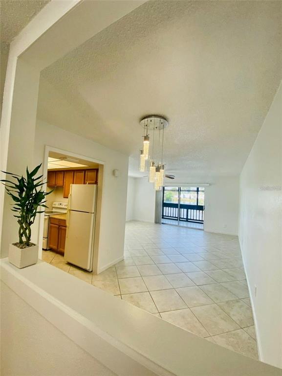 A view from a half-wall into a tiled living area with a modern pendant light — 633 N KEENE ROAD APT C, CLEARWATER, FL
