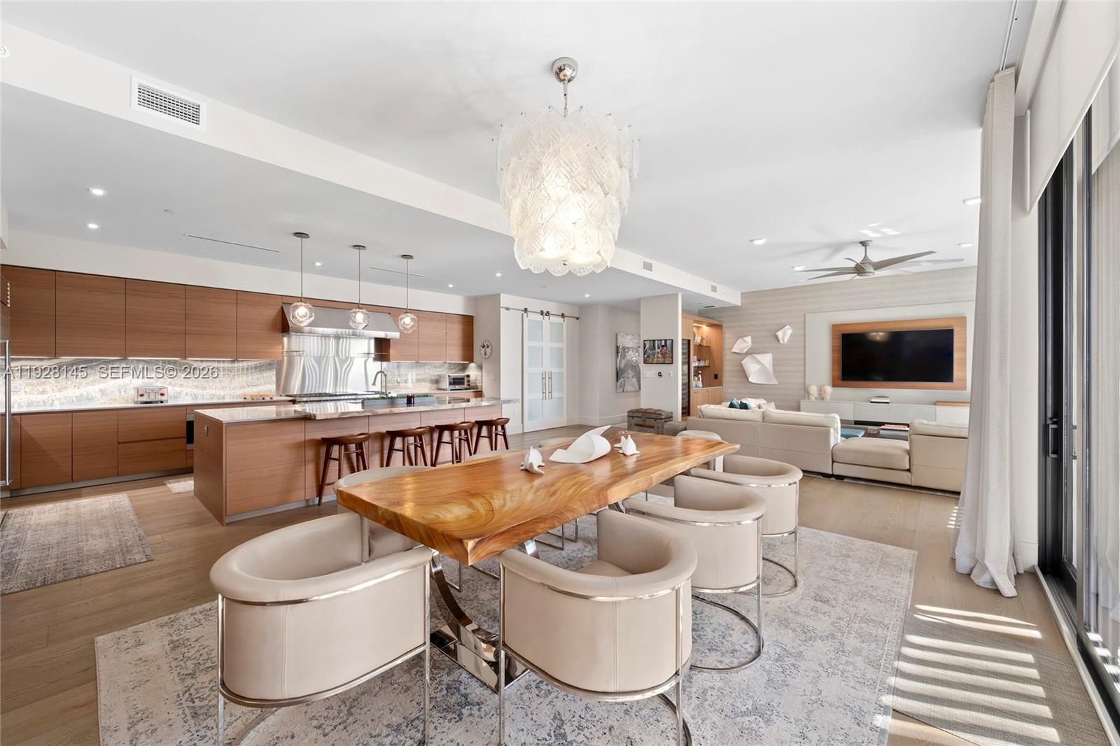 An open-concept living area features a wooden dining table, modern kitchen, and beige sectional sofa — 3581 E Glencoe St # 403, Miami FL 33133, MIAMI, FL
