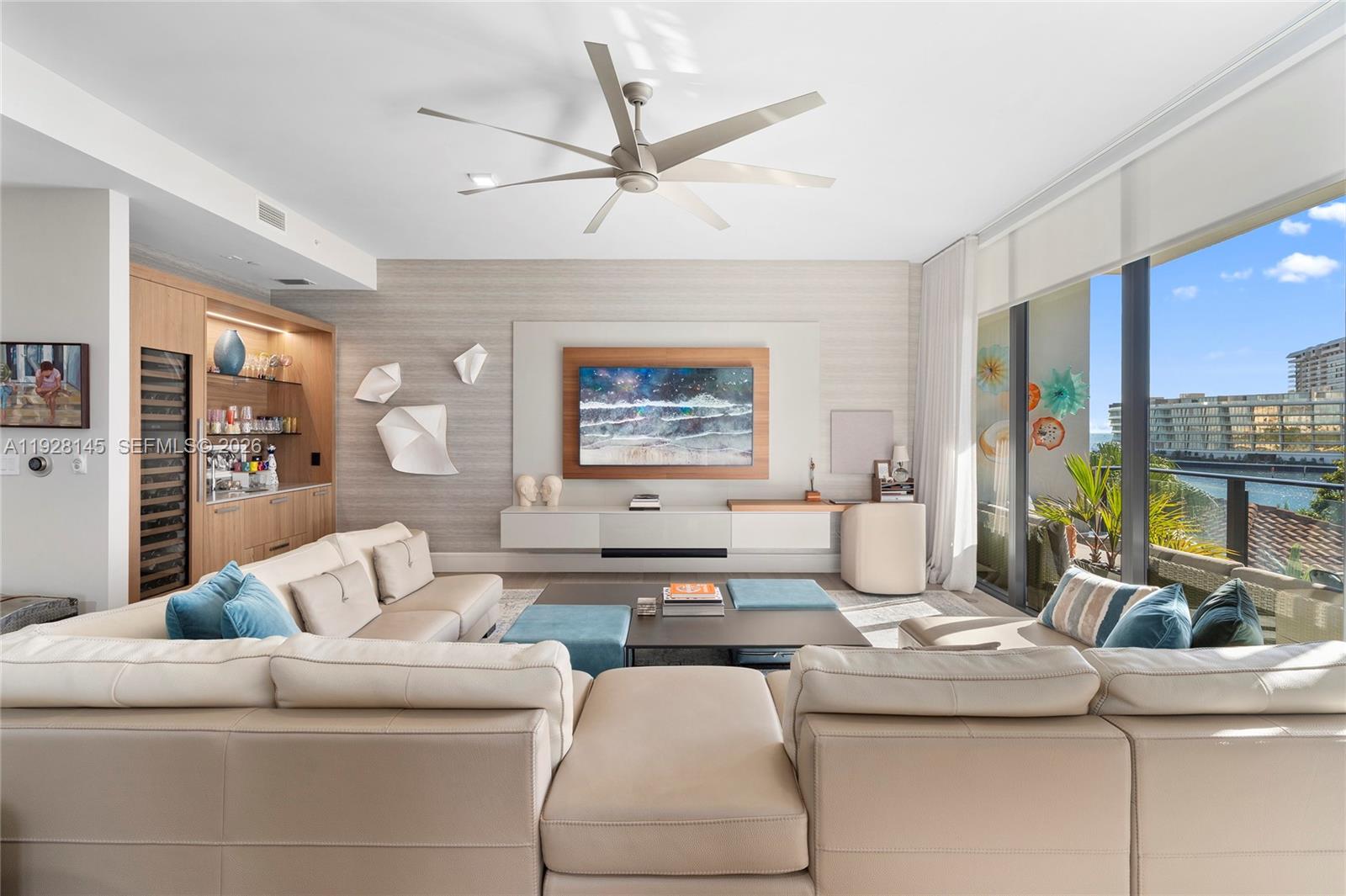 A modern living room features a large sectional sofa, a wall-mounted television, and balcony views — 3581 E Glencoe St # 403, Miami FL 33133, MIAMI, FL