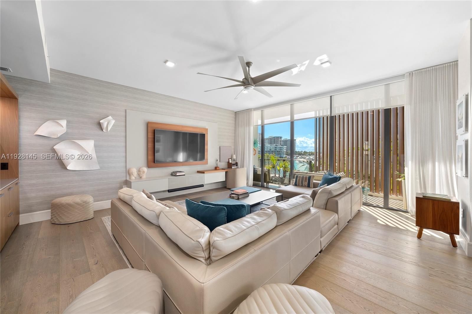 A modern living room features a large sectional sofa, wood flooring, and floor-to-ceiling windows — 3581 E Glencoe St # 403, Miami FL 33133, MIAMI, FL