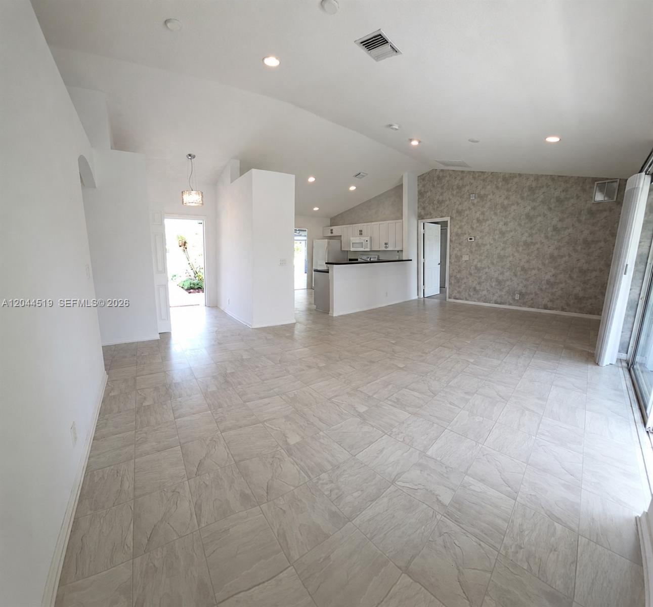 An open-concept living area features light-colored tile flooring, vaulted ceilings, and a kitchen pass-through — 547 High Hawk Cir # 541, Vero Beach FL 32962, VERO BEACH, FL