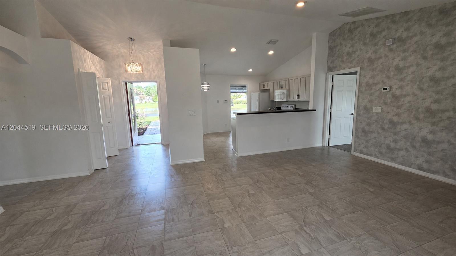 An open-concept living area features light-colored tile flooring, a kitchen with white cabinets, and an entryway — 547 High Hawk Cir # 541, Vero Beach FL 32962, VERO BEACH, FL