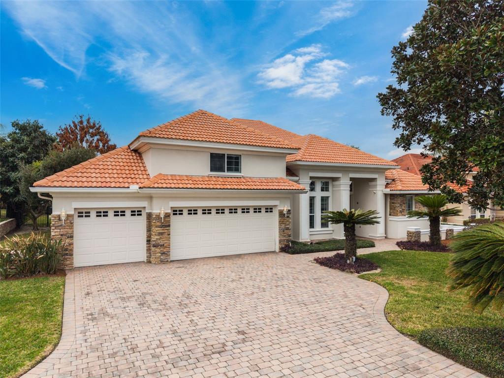 A two-story house with a tile roof, stone accents, and a paved driveway — 1950 ELKHORN COURT, LONGWOOD, FL