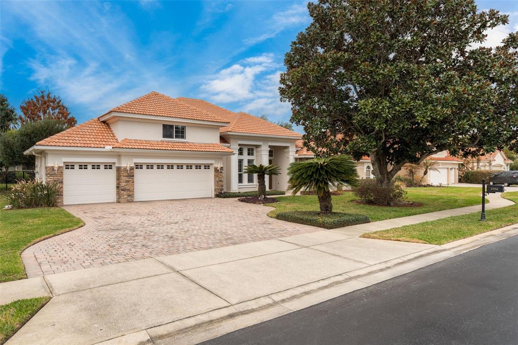 A two-story house with a tile roof, stone accents, and a paved driveway — 1950 ELKHORN COURT, LONGWOOD, FL