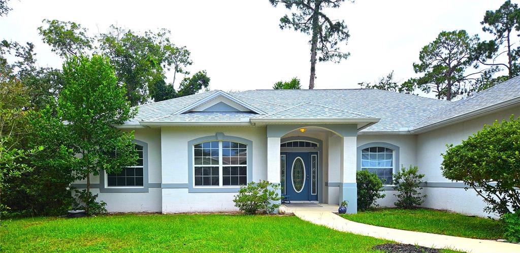A single-story house with a gray exterior, a two-car garage, and a concrete driveway — 25 FENIMORE LANE, PALM COAST, FL
