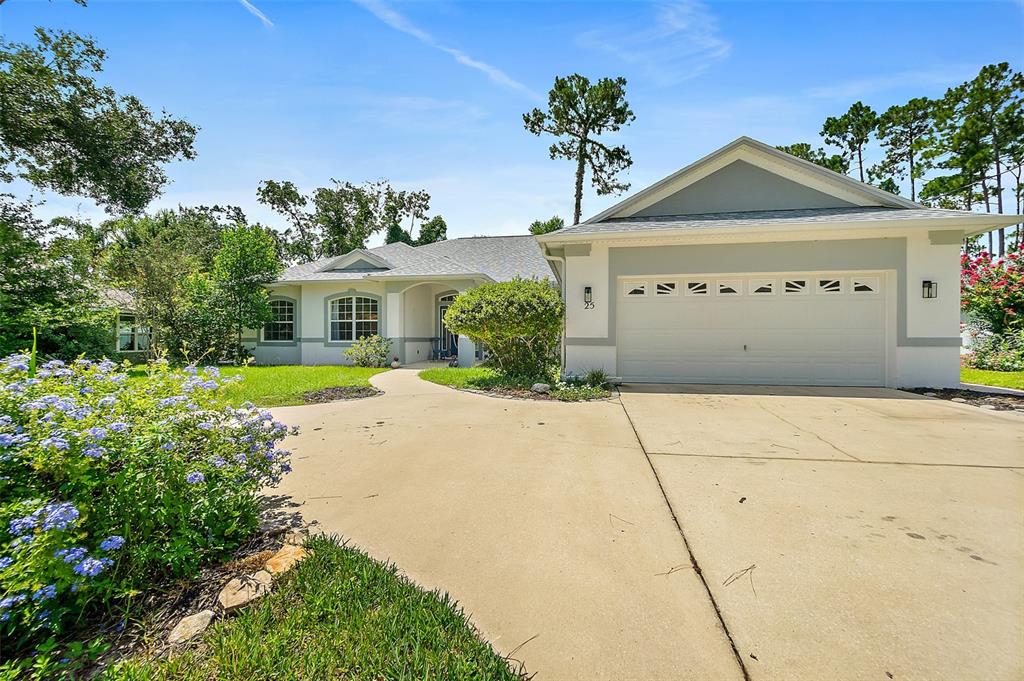 A single-story house with a two-car garage, a concrete driveway, and a landscaped front yard — 25 FENIMORE LANE, PALM COAST, FL