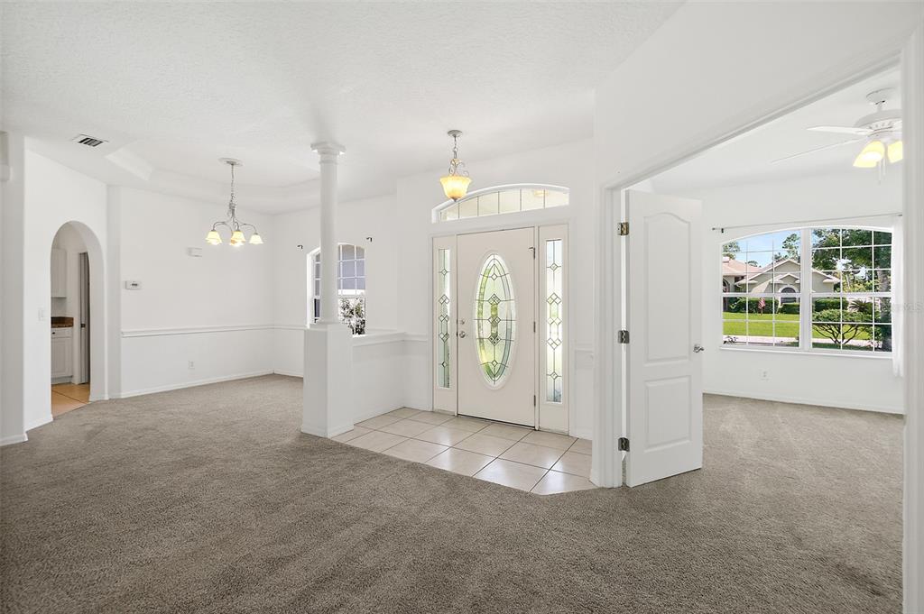 An entryway with tile flooring, a white front door, and carpeted rooms on either side — 25 FENIMORE LANE, PALM COAST, FL