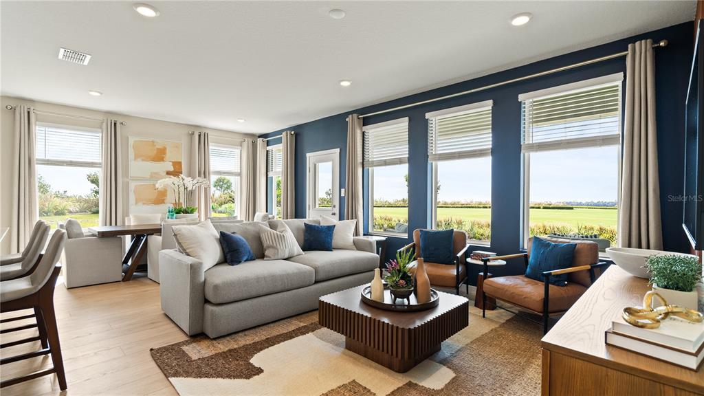A living room features a grey sofa, two leather chairs, and large windows overlooking grass — 159 GLENFIELD DRIVE, DAVENPORT, FL