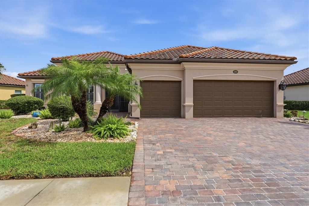 A single-story house with a tiled roof, a three-car garage, and a paved driveway — 13652 CLASSICO COURT, VENICE, FL