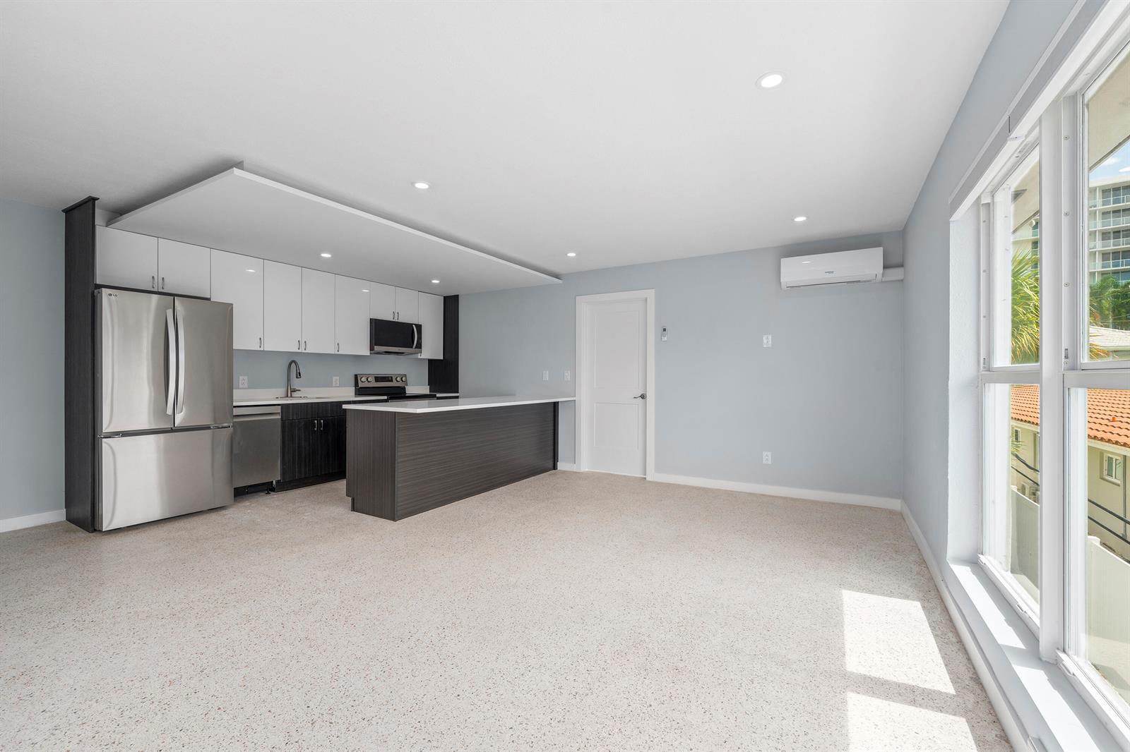 A modern kitchen with white and dark wood cabinetry opens into a spacious living area — 3220 NE 7th Place # 3, Pompano Beach FL 33062, POMPANO BEACH, FL