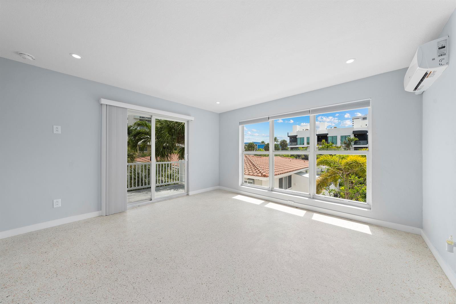 An empty room with light gray walls, terrazzo flooring, a sliding glass door, and windows — 3220 NE 7th Place # 3, Pompano Beach FL 33062, POMPANO BEACH, FL
